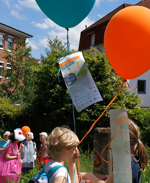 Foto vom Dellbrückentag 2019 mit BesucherInnen, KünstlerInnen, Luftballons und Plakat