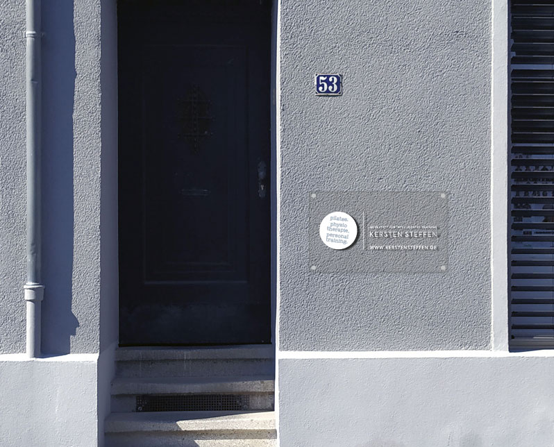 Transparentes Schild mit weißen Elementen an der Fassade des Studios